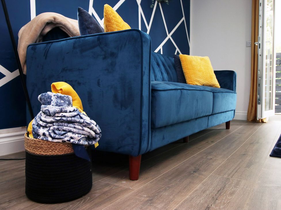 A living room with a blue sofa and a basket of blankets at 2 bed Cardiff city centre apartment in Cardiff