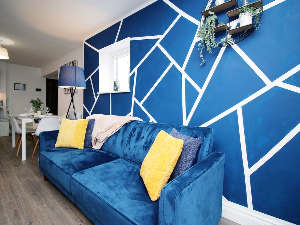 A living room with a blue sofa and wall art at 2 bed Cardiff city centre apartment in Cardiff