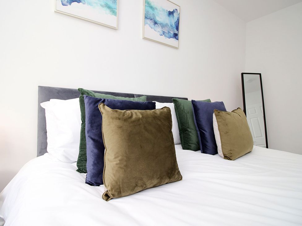 A bed with pillows and wall art in a bedroom at 2 bed Cardiff city centre apartment Cardiff