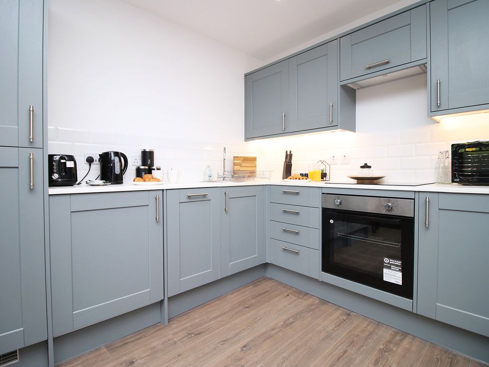 A kitchen with gray cabinets and appliances at 2 bed Cardiff city centre apartment, Cardiff