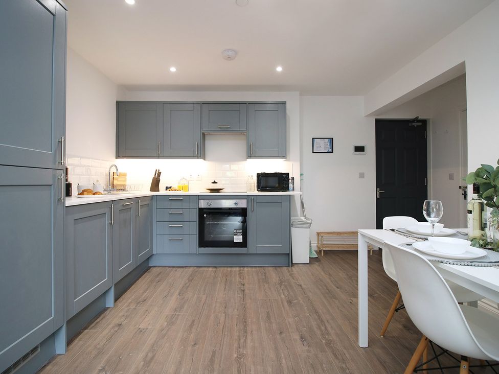 A kitchen with blue cabinets and a dining table at 2 bed Cardiff city centre apartment Cardiff