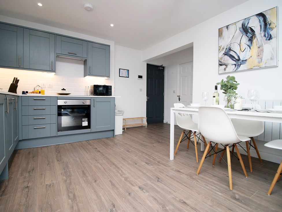 A kitchen with cabinets and dining table at 2 bed Cardiff city centre apartment in Cardiff