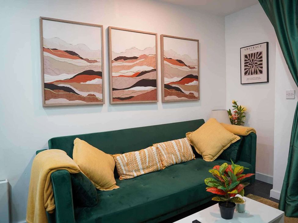 A living room with a green sofa and wall art at Ground Floor Apartment Sleeps 4 with Parking Cardiff