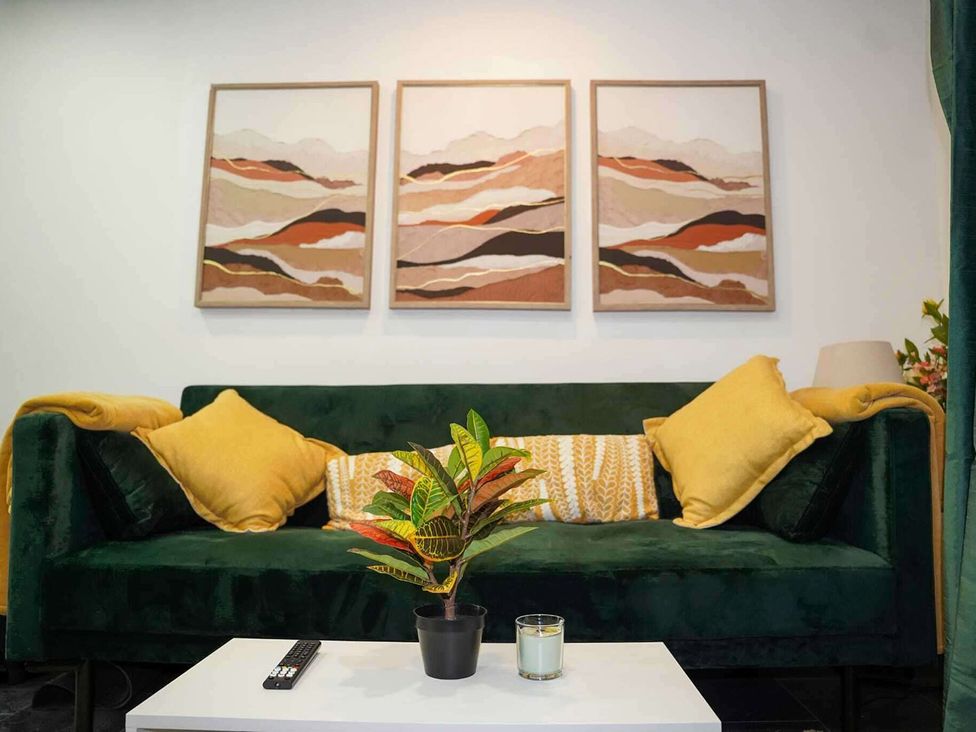 A living room with a green sofa and wall art at Ground Floor Apartment Sleeps 4 with Parking Cardiff