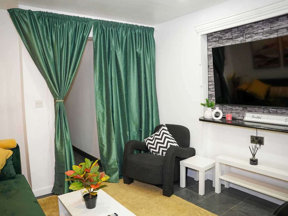 A living room with a television and a chair at Ground Floor Apartment Sleeps 4 with Parking Cardiff