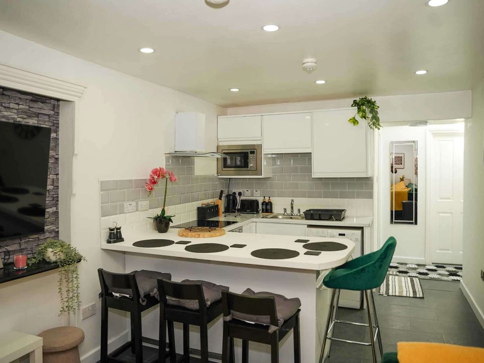 A kitchen with bar stools and appliances at Ground Floor Apartment Sleeps 4 with Parking in Cardiff