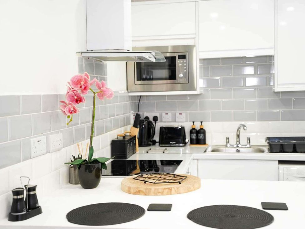 A kitchen with a microwave, stove, and sink at Ground Floor Apartment Sleeps 4 with Parking Cardiff