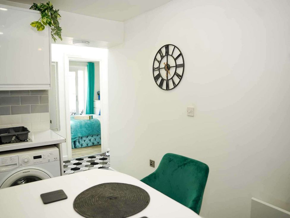A kitchen with a washing machine and a clock at Ground Floor Apartment Sleeps 4 with Parking in Cardiff