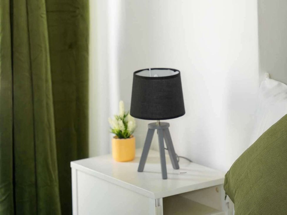 A bedroom with a lamp and plant on a nightstand at Ground Floor Apartment Sleeps 4 with Parking Cardiff