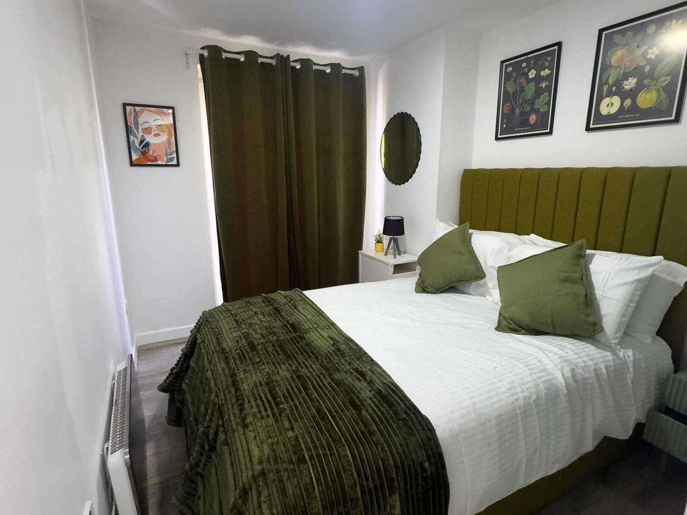 A bedroom with a bed and green curtains at Ground Floor Apartment Sleeps 4 with Parking Cardiff