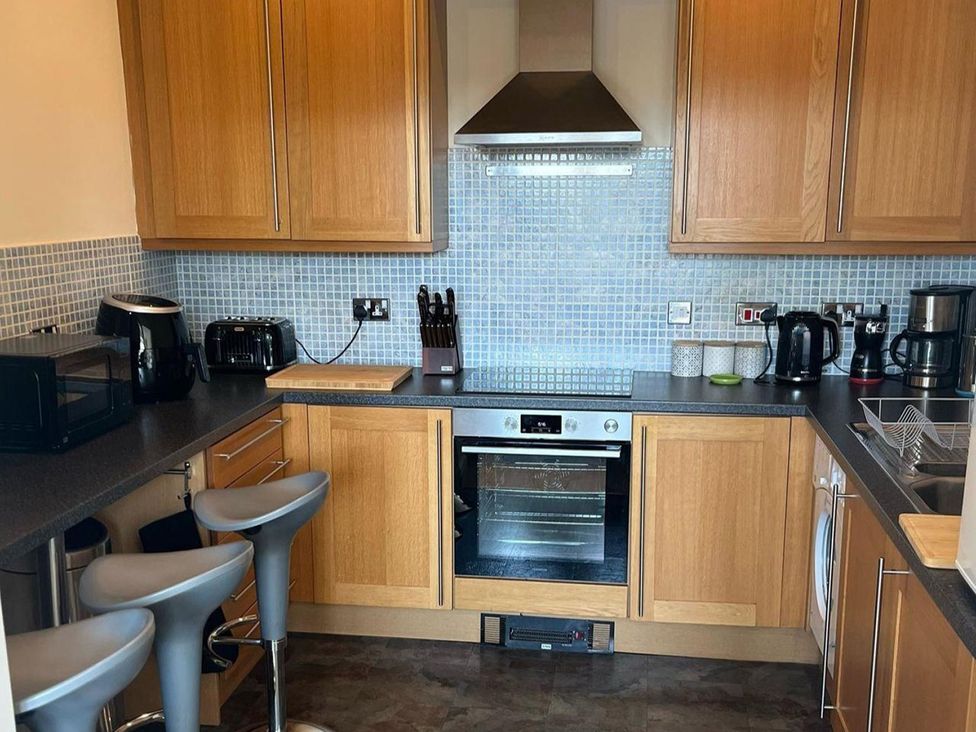 A kitchen with appliances and bar stools at Cardiff Apartment, sleeps 6, Castle and Stadium nearby, Cardiff