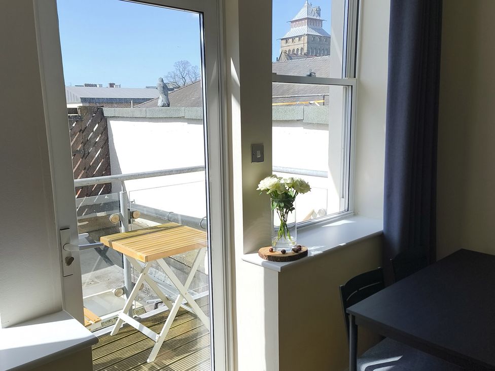 A dining room with a view of a balcony and flowers in a vase at Cardiff Apartment, sleeps 6, Castle and Stadium nearby, Cardiff
