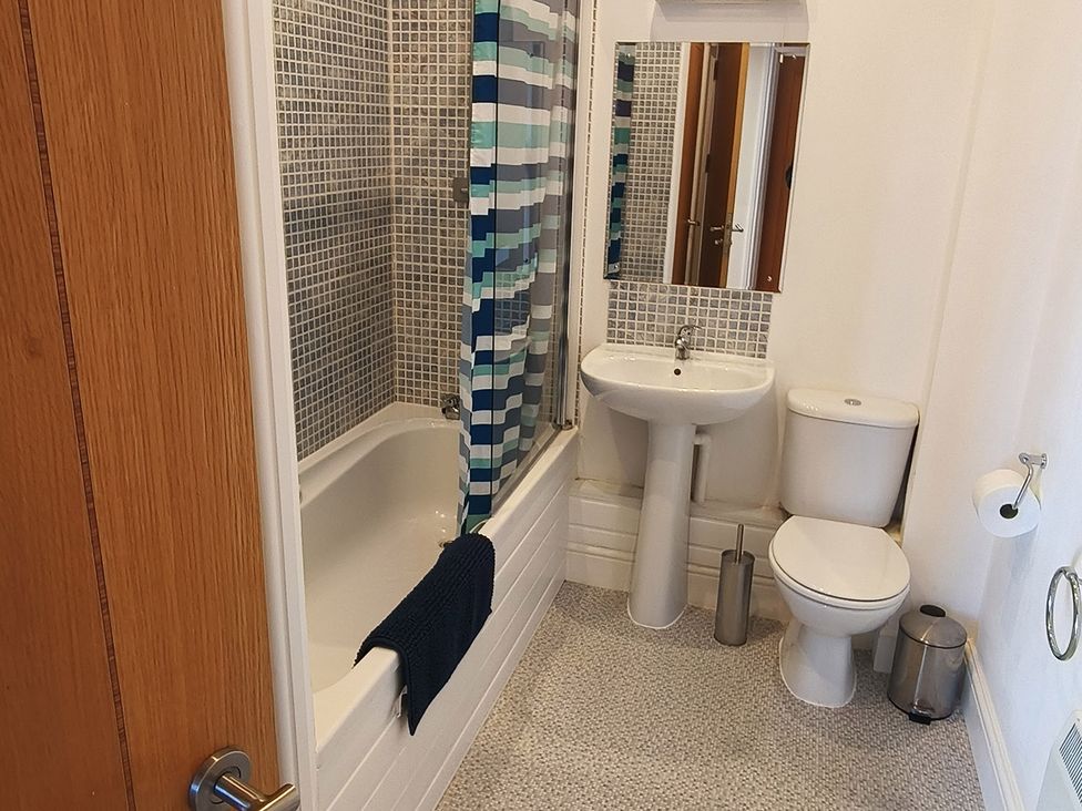 A bathroom with bathtub, sink, toilet, and mirror at Cardiff Apartment, sleeps 6, Castle and Stadium nearby Cardiff
