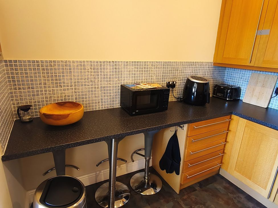 A kitchen with a microwave and wooden bowl at Cardiff Apartment, sleeps 6, Castle and Stadium nearby Cardiff