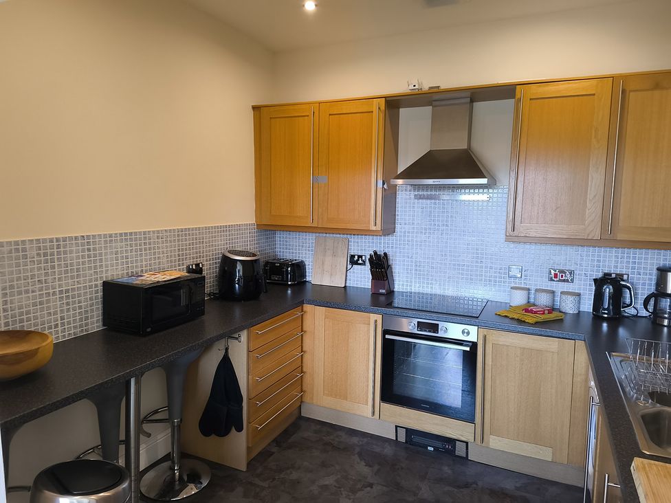 A kitchen with wooden cabinets and appliances at Cardiff Apartment, sleeps 6, Castle and Stadium nearby Cardiff