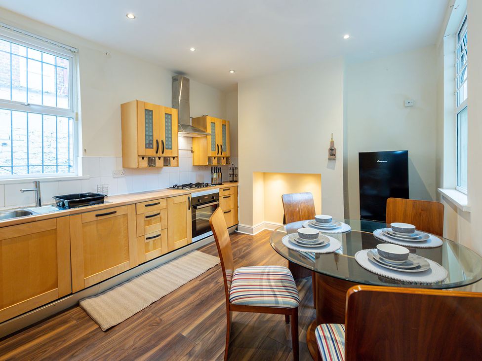 A kitchen with wooden cabinets and a dining table at 5 Bed House, sleeping 10 in the City Centre, Liverpool