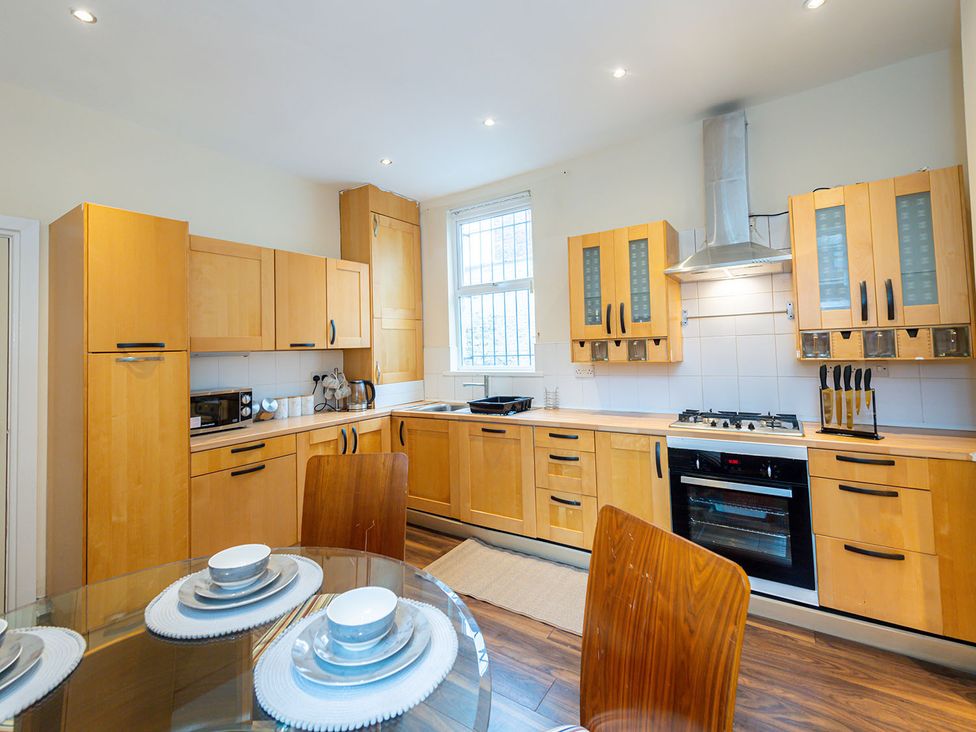 A kitchen with wooden cabinets and a dining table at 5 Bed House, sleeping 10 in the City Centre Liverpool
