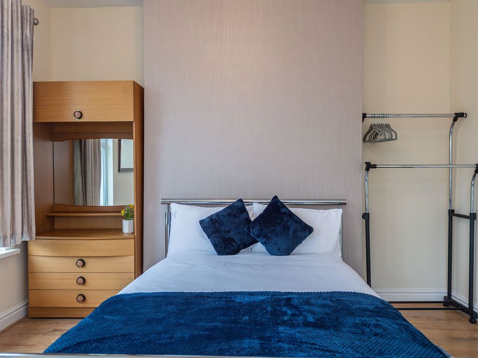 A bedroom with a bed and a wooden wardrobe at 5 Bed House, sleeping 10 in the City Centre Liverpool