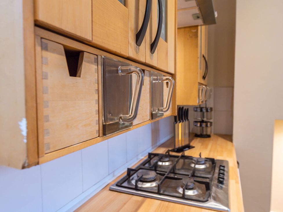 A kitchen with wooden cabinets and a gas stove at 5 Bed House, sleeping 10 in the City Centre Liverpool
