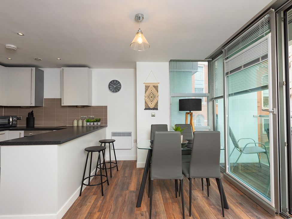 A kitchen with stools and dining table at City Centre Apartment, 2 bed with Free Parking, Liverpool