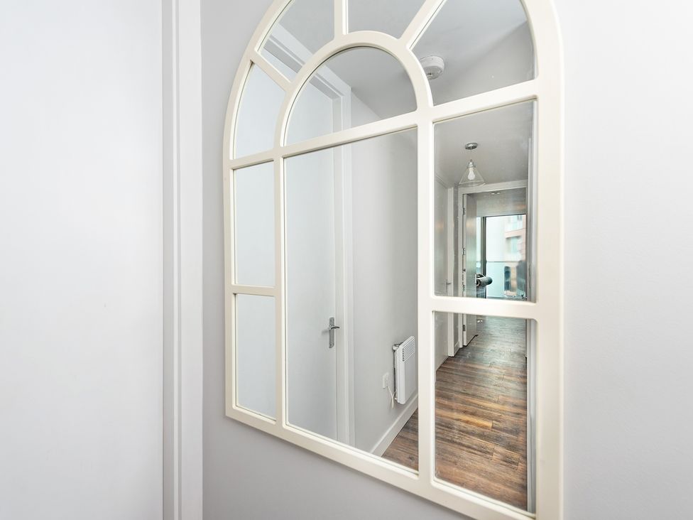 A mirror reflecting a hallway with a door and light fixture at City Centre Apartment, 2 bed with Free Parking Liverpool