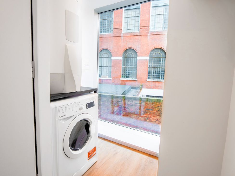 A laundry room with a washing machine and a window at Luxury City Centre Apartment, Prime Location in Liverpool