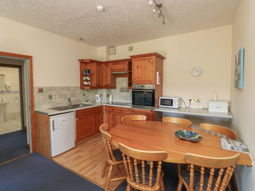 A kitchen with wooden cabinets and a dining table at Willow in Kingsteignton