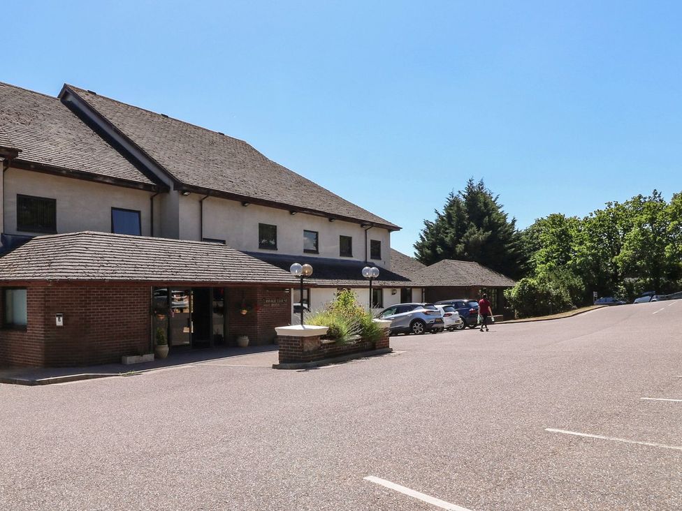 An outdoor area with a building and parking lot at Goldfinch in Kingsteignton