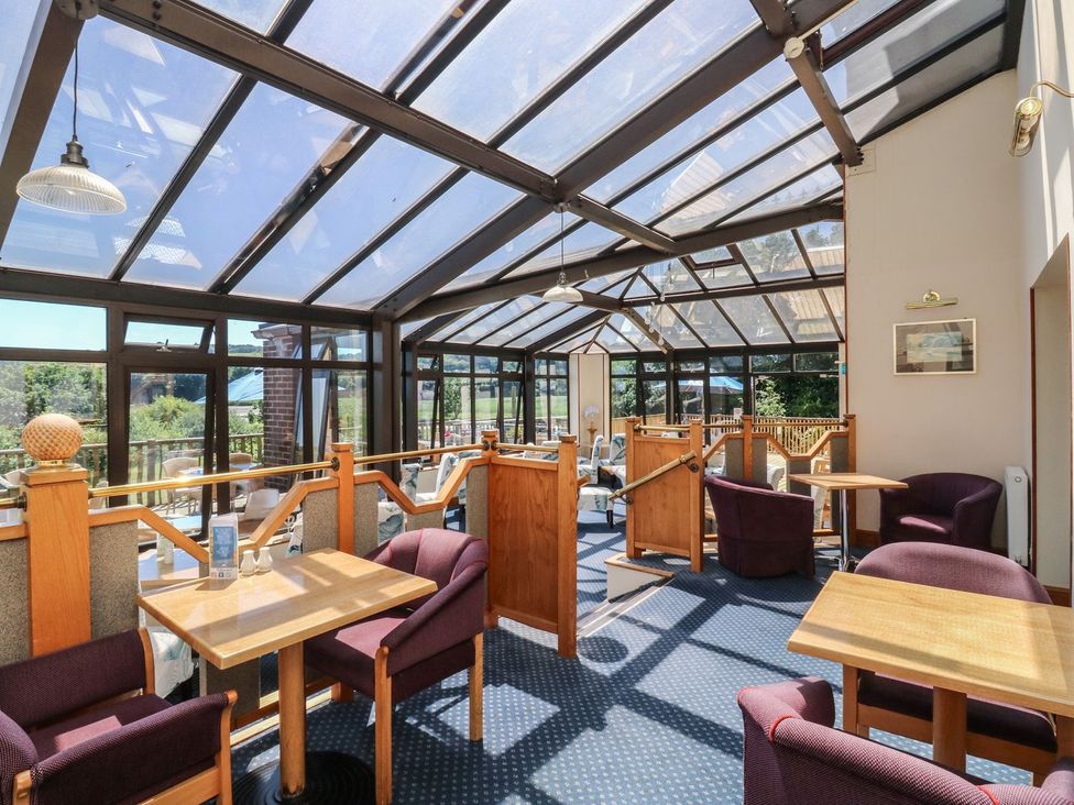 A conservatory with tables and chairs at Moorland in Kingsteignton