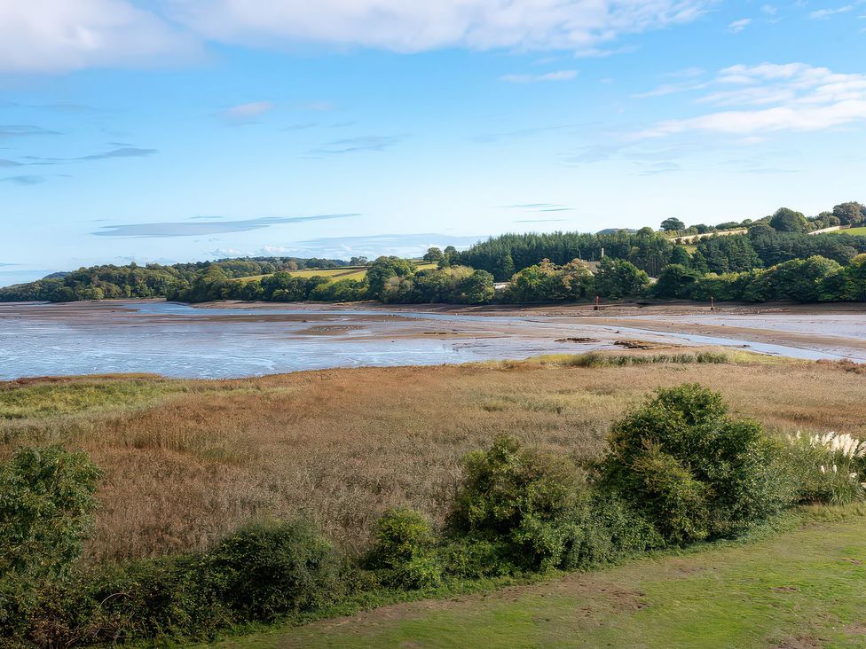 A view of water and grass with trees and hills at Moorhen in Kingsteignton