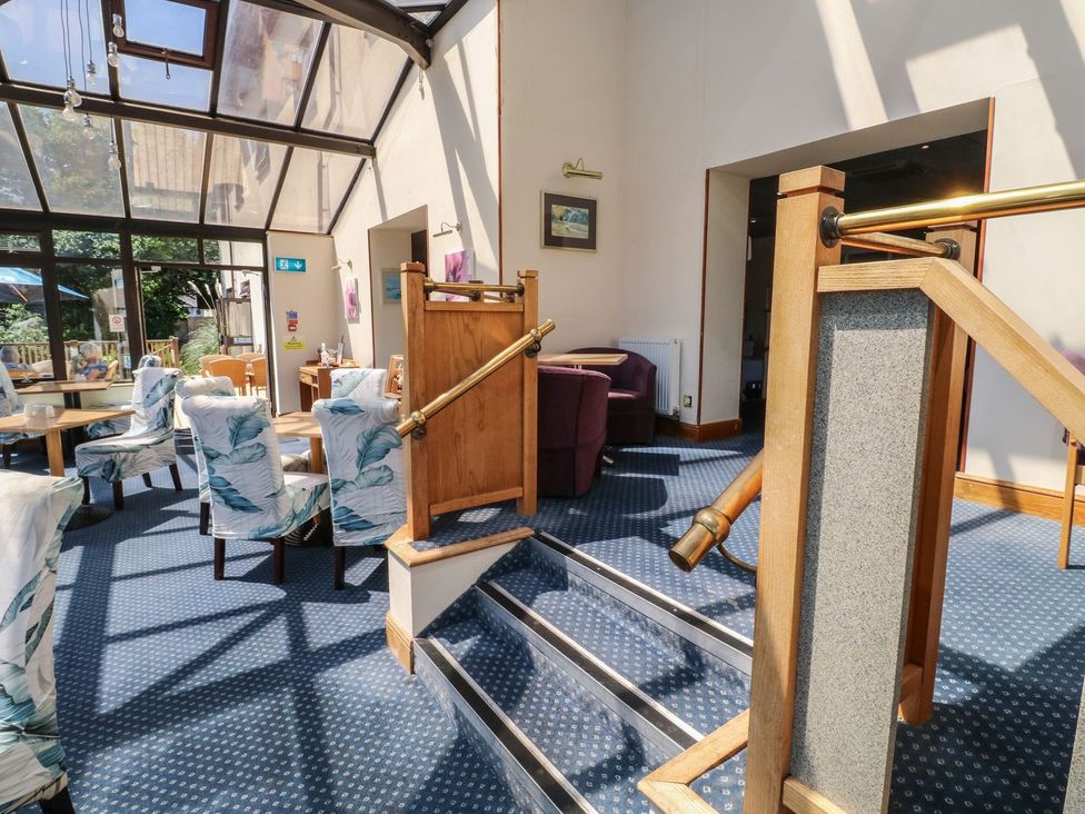 A conservatory with seating and tables at Moorhen in Kingsteignton