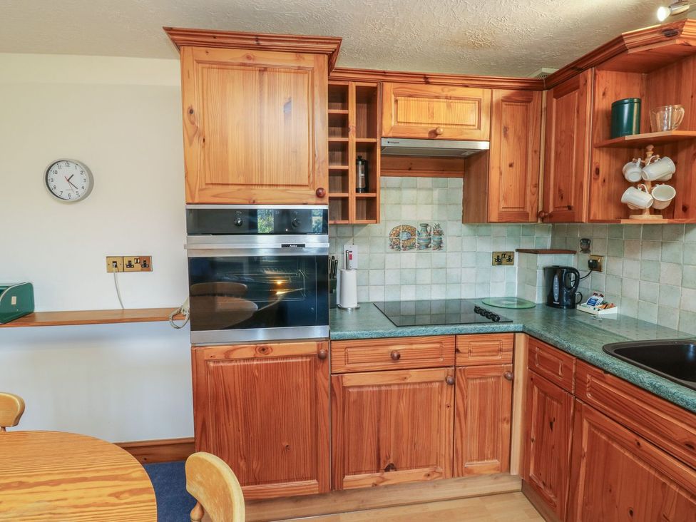 A kitchen with wooden cabinets and counter at Moorhen in Kingsteignton