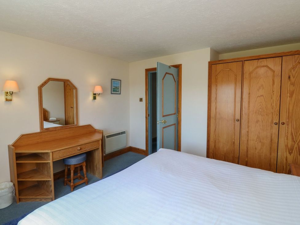 A bedroom with a bed, desk, chair, and wardrobe at Puffin in Kingsteignton