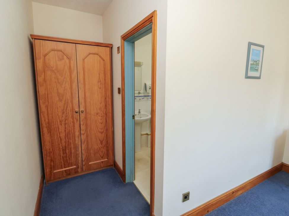 A corridor leading to a bathroom with a wardrobe and sink at Egret in Kingsteignton