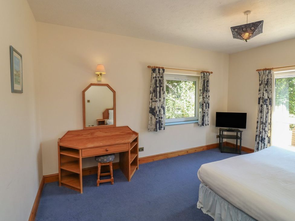 A bedroom with a bed, table, mirror and tv at Avocet in Kingsteignton