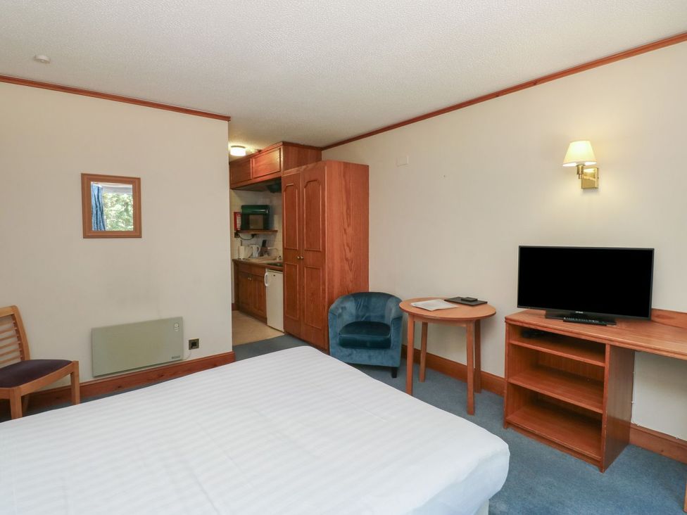 A bedroom with a bed and kitchenette at Sycamore in Kingsteignton