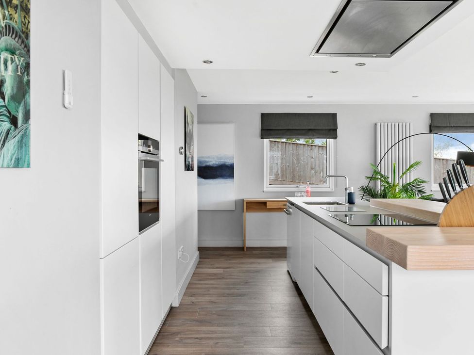 A kitchen with white cabinets and a wooden countertop at Huxham View & Annex in Kingsteignton