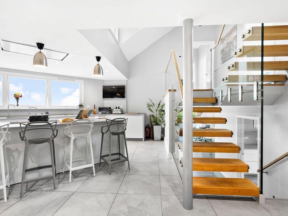 A kitchen with bar stools and a staircase at Huxham View & Annex in Kingsteignton