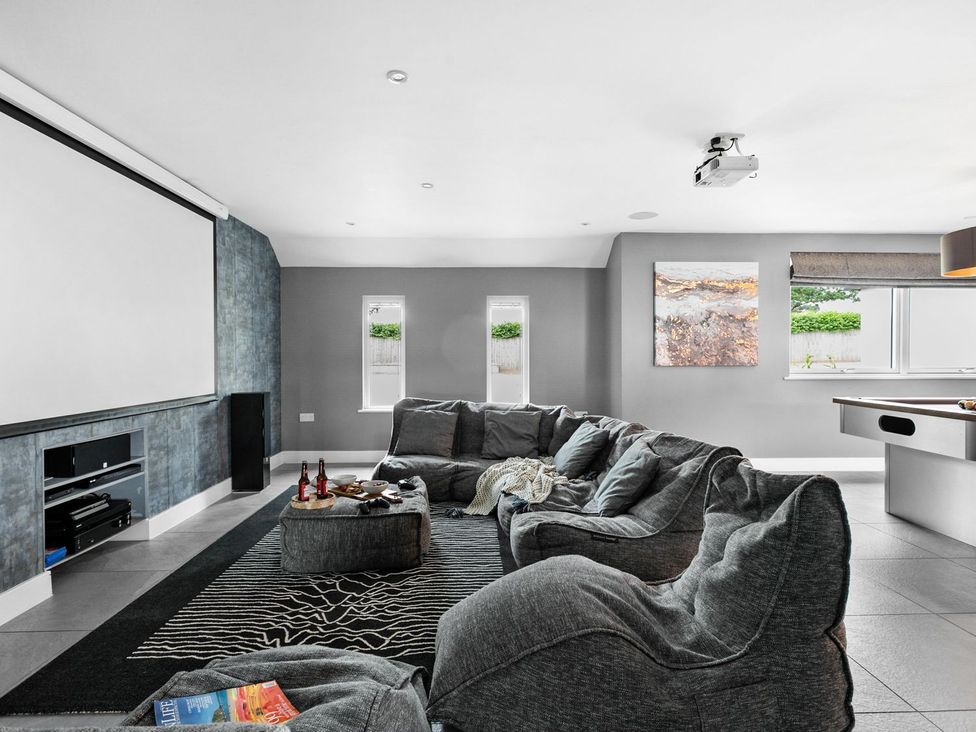A snug with a projector and large sofa at Huxham View & Annex in Kingsteignton