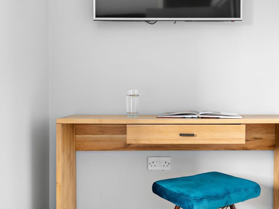 An office with a desk, glass of water, and a book at Huxham View & Annex in Kingsteignton