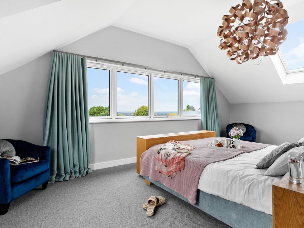 A bedroom with a bed and armchair at Huxham View & Annex in Kingsteignton