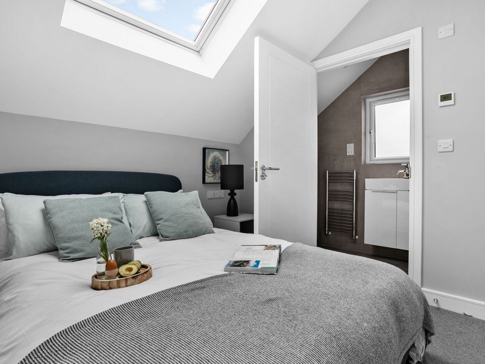 A bedroom with a bed and a doorway to a bathroom at Huxham View & Annex Kingsteignton