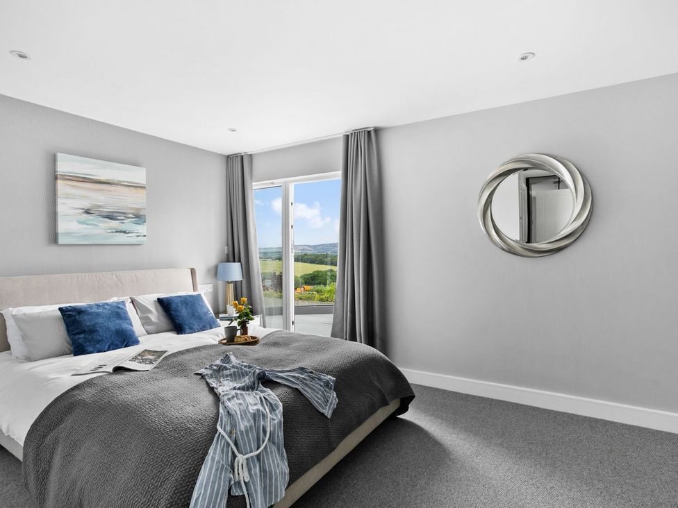 A bedroom with a bed and sliding door at Huxham View & Annex Kingsteignton