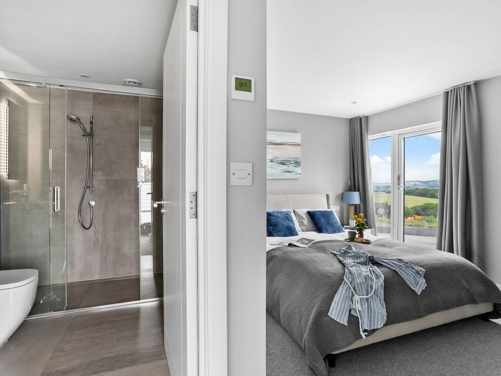 A bathroom with shower and a bedroom with a bed at Huxham View & Annex in Kingsteignton
