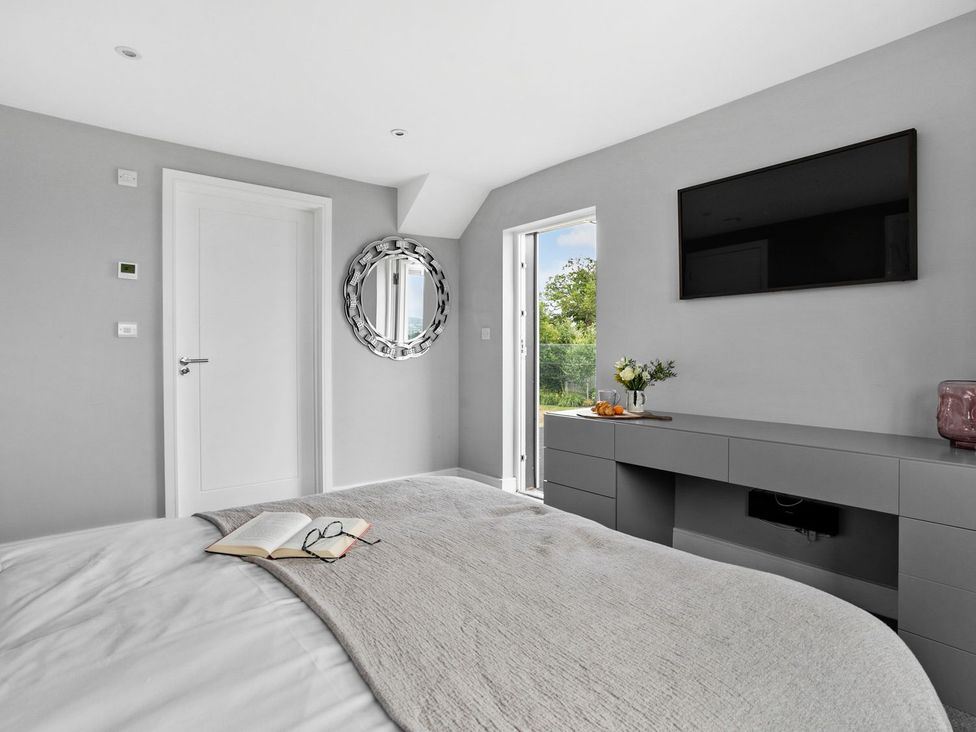 A bedroom with a bed and a TV at Huxham View & Annex in Kingsteignton
