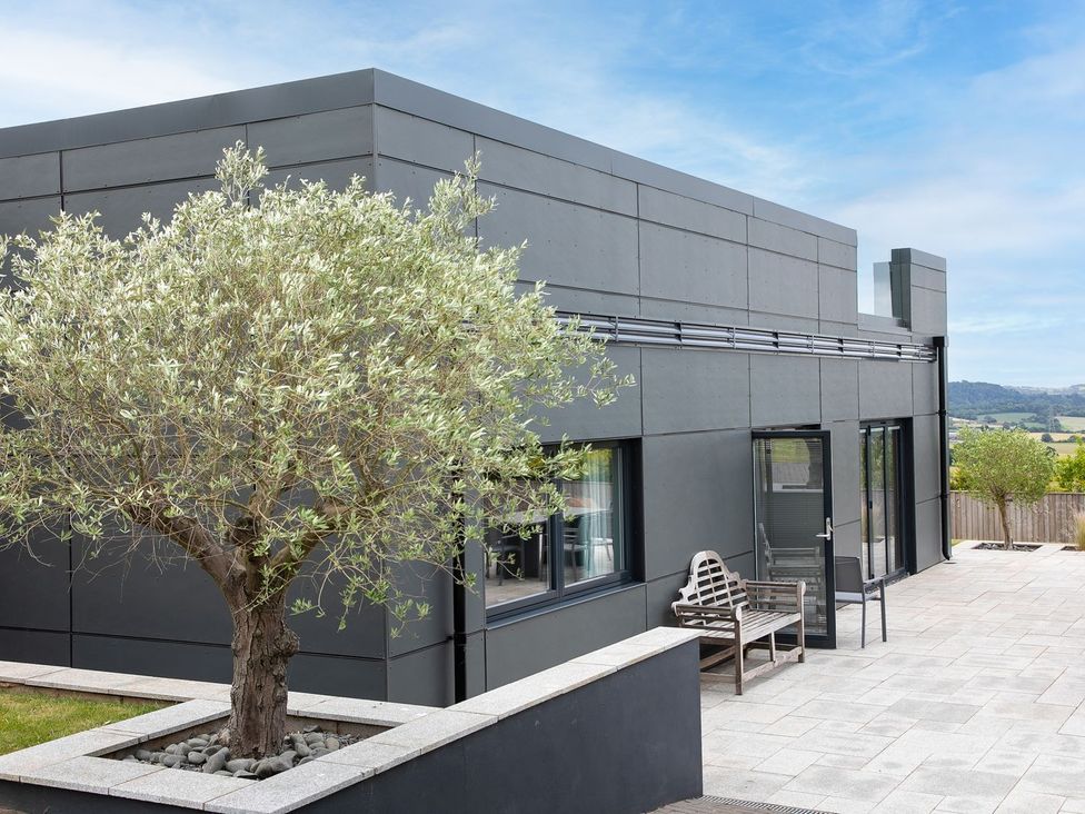 An outdoor area featuring a building, tree, and bench at Huxham View & Annex in Kingsteignton