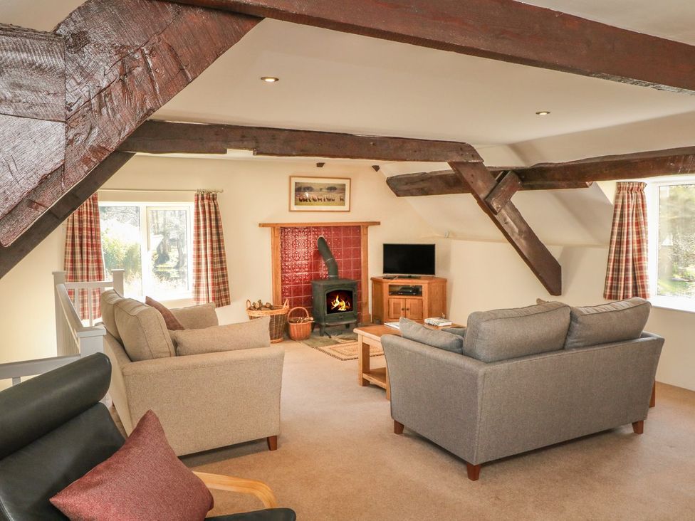 A living room with a fireplace and seating at Upper Barn Cottage in Minehead