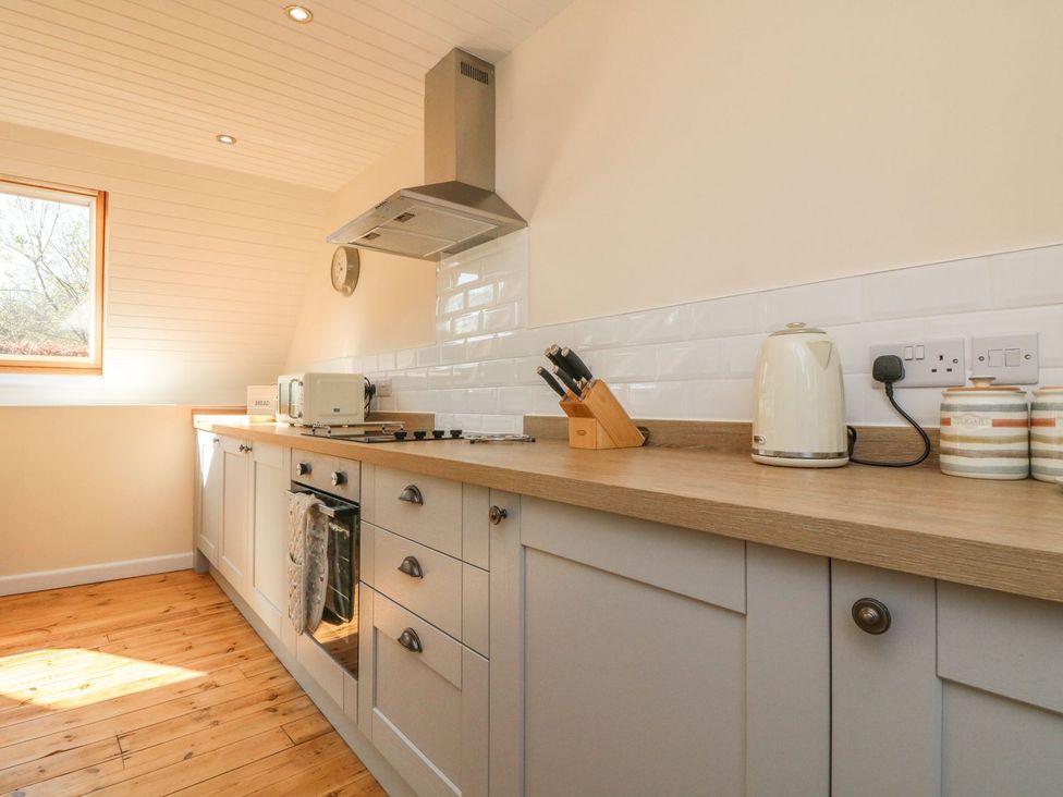 A kitchen with a window and appliances at Upper Barn Cottage in Minehead