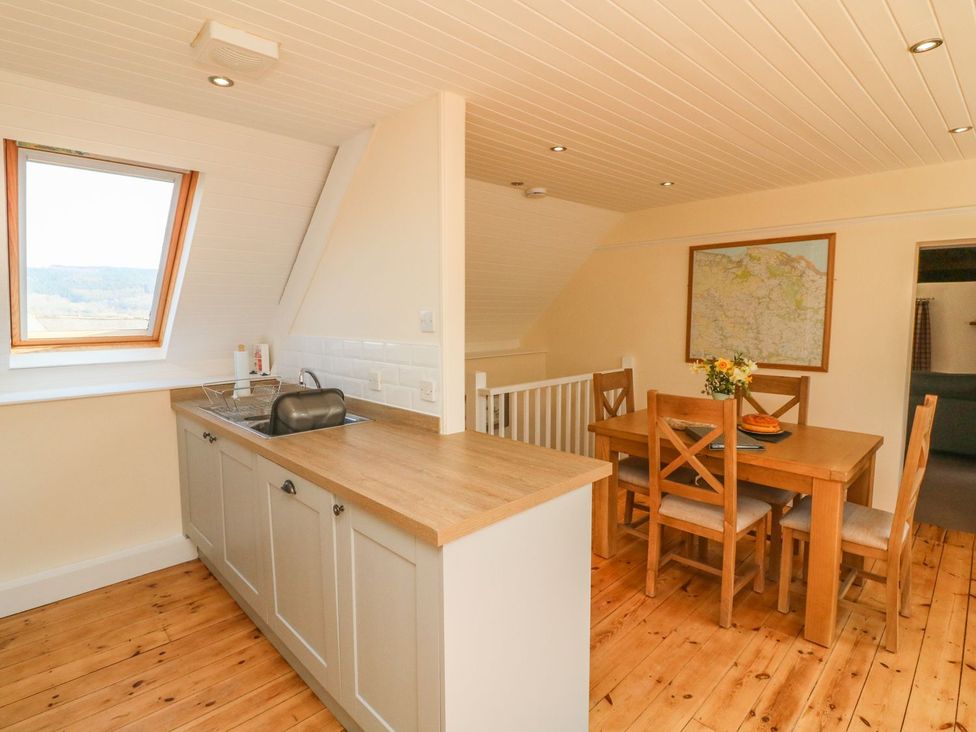 A kitchen with a dining area and a window at Upper Barn Cottage in Minehead