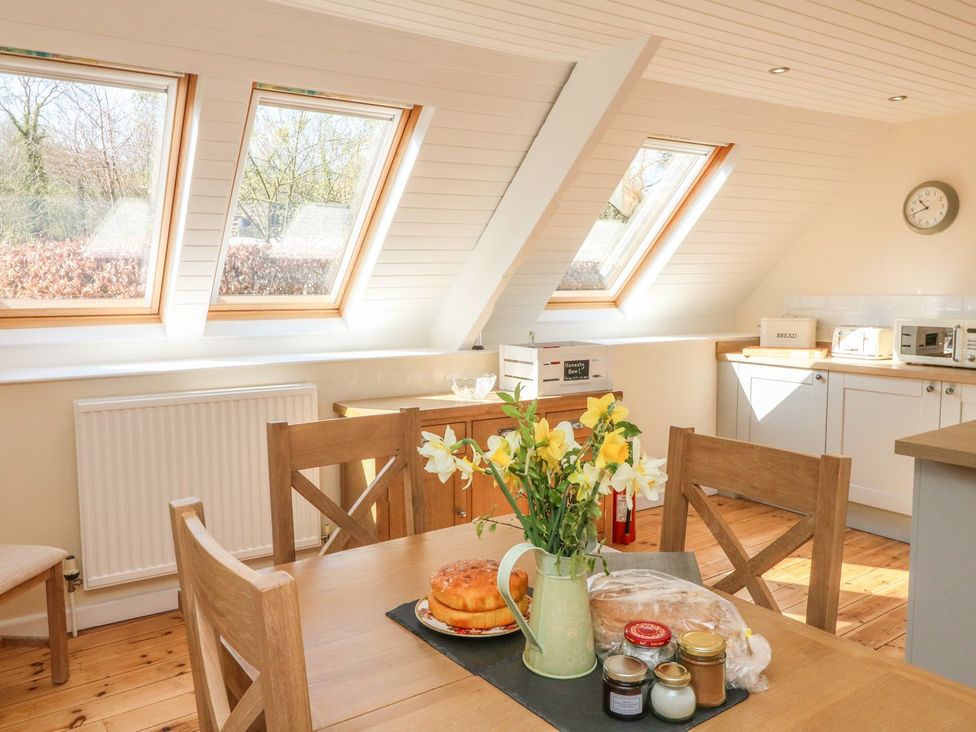 A kitchen with a table and flowers at Upper Barn Cottage Minehead